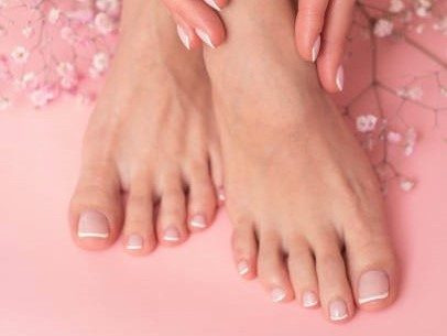 Perfect done french manicure and pedicure on pink background.